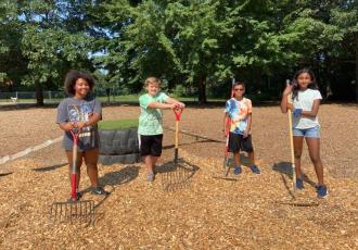 kids standing and holding gardening equipment