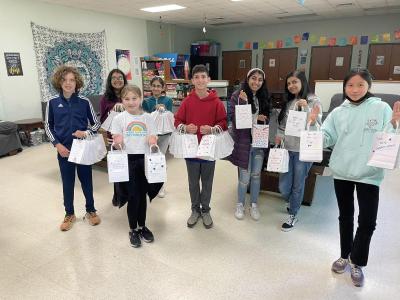 children standing in a room holding white paper bags