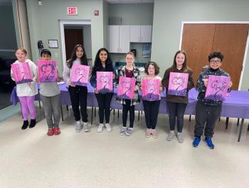 children showing off paintings they did, all the paintings are the same 