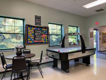 image of teen center with ice hockey table, flowers on a table, and art on the wall