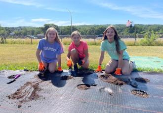 kids sitting on the grass with gardening equipment planting flowers