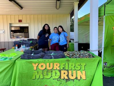 kids standing at a desk that says your first mud run